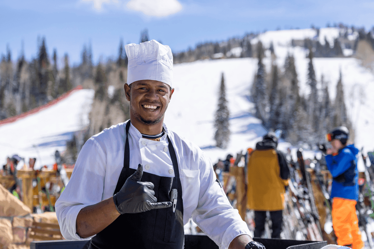 Employee posing for photo with ski run in background.