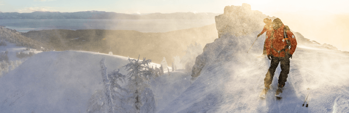 2 ski patrollers looking over the edge of a bowl.